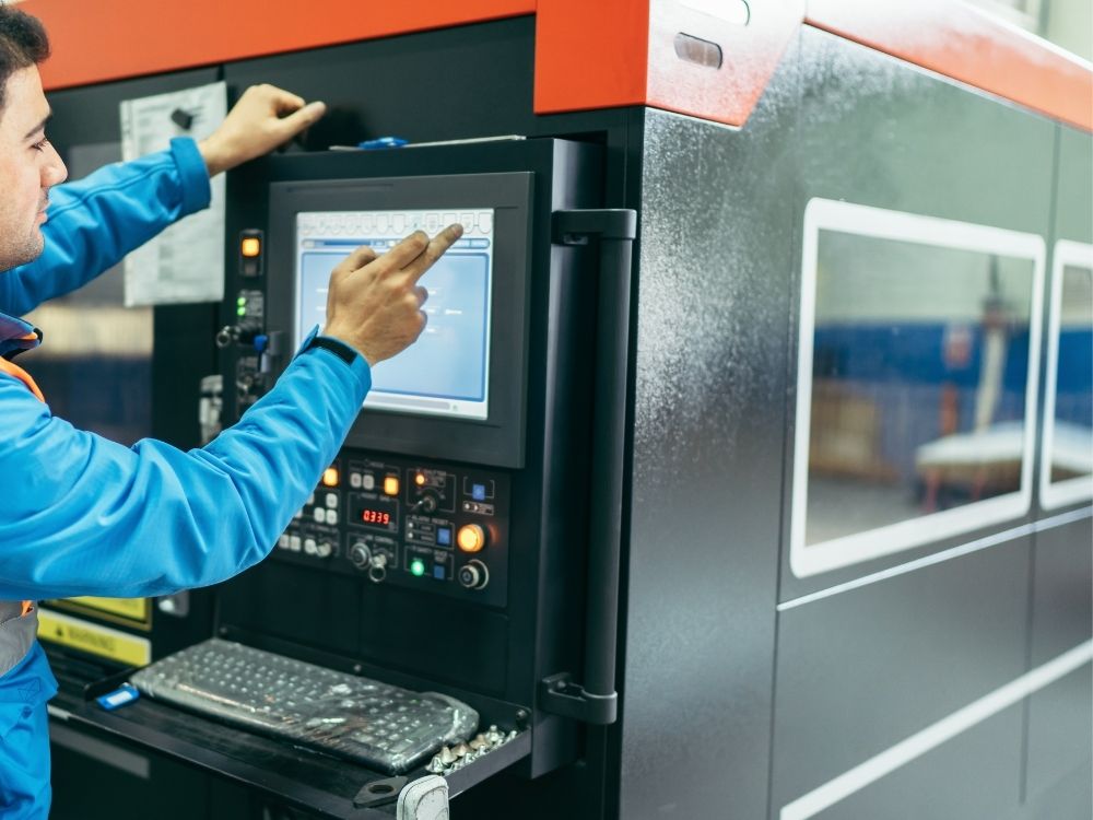 Bir CNC operatörünün hassas şekilde bir CNC makinesini kontrol ettiği sahne.